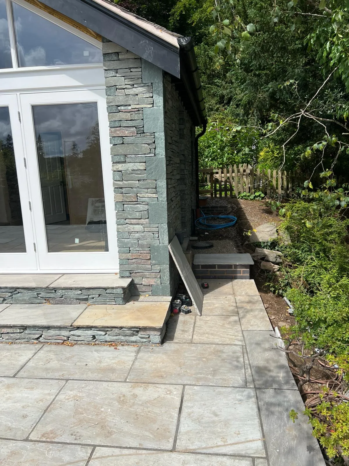 A patio with a stone wall and a white door.