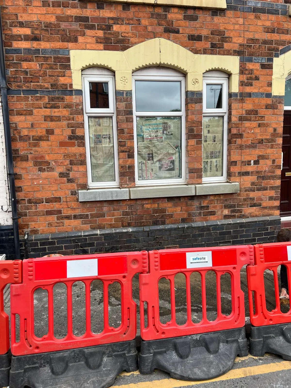 A row of red barricades in front of a brick building.