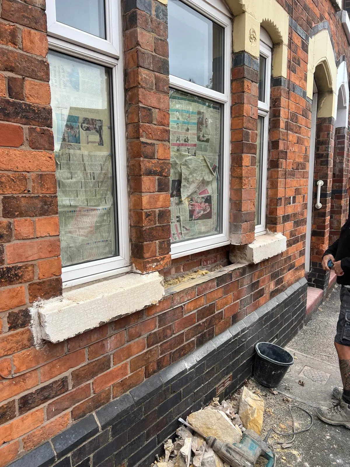 A man standing in front of a brick building.