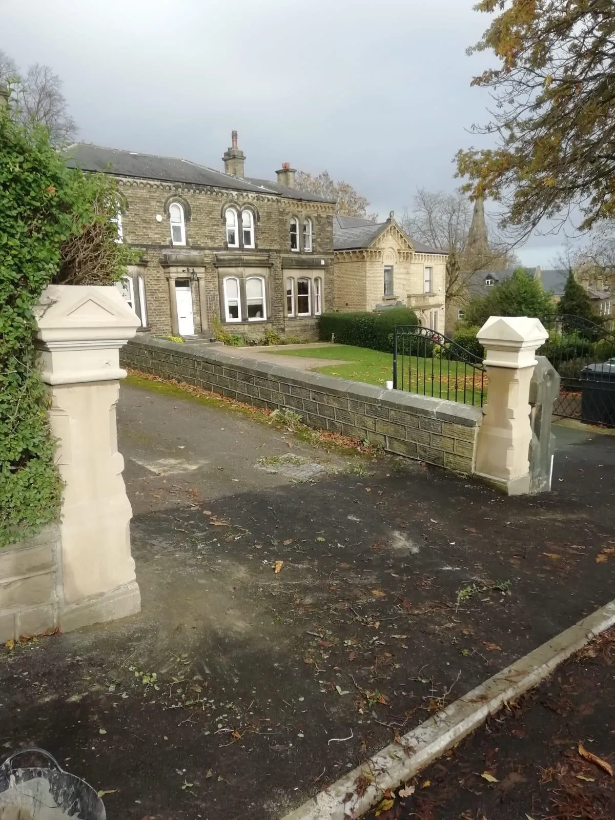 A driveway with a gate and a house in the background.